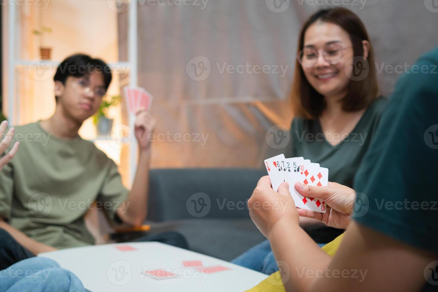 Diverse people playing a card game in the living room, Asian family playing games together photo