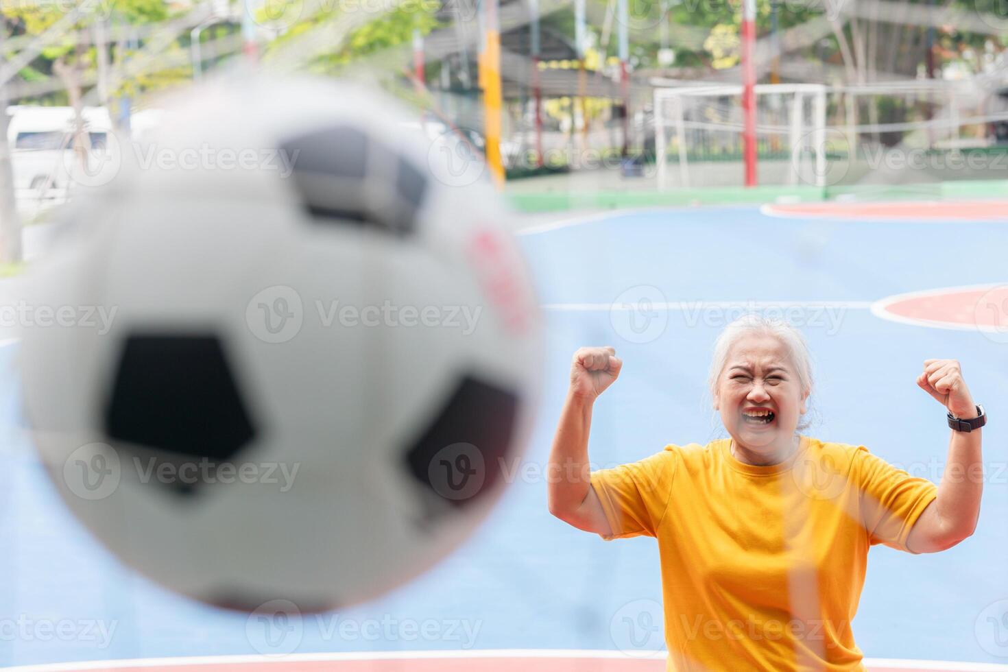 Active senior woman playing football in the urban outdoor court, Asian senior woman with a soccer ball, healthy life concepts photo