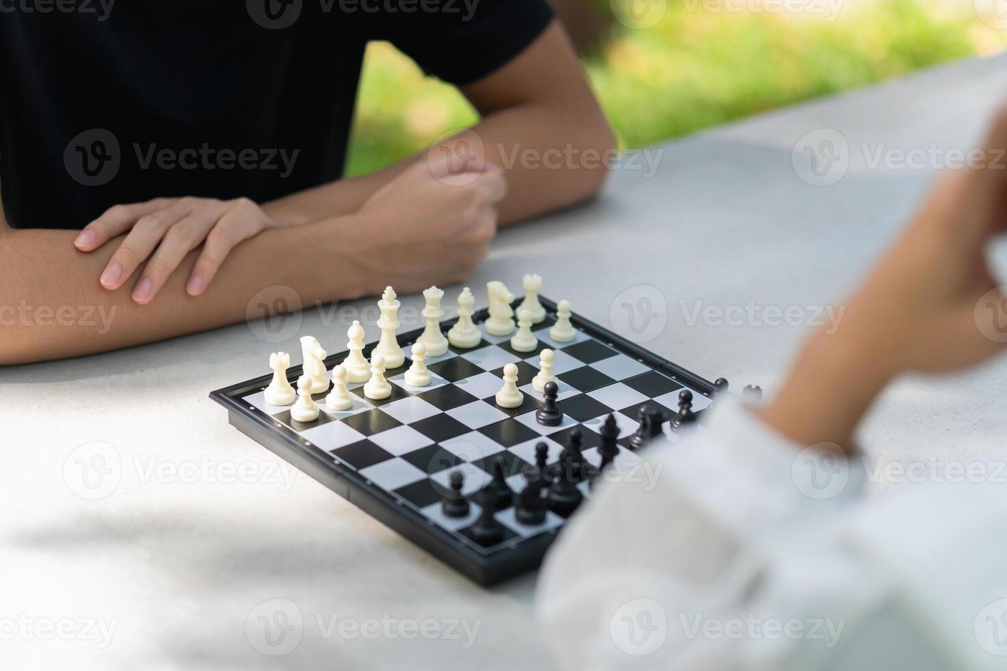 Close-up of a mother playing chess in a park with a son photo