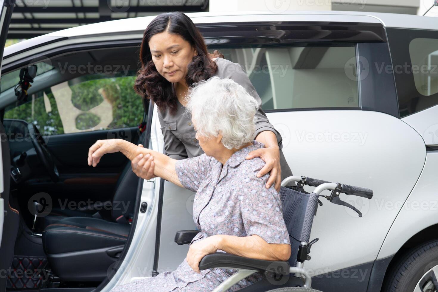 Caregiver help and support asian elderly woman sitting on wheelchair prepare get to her car to travel in holiday. photo