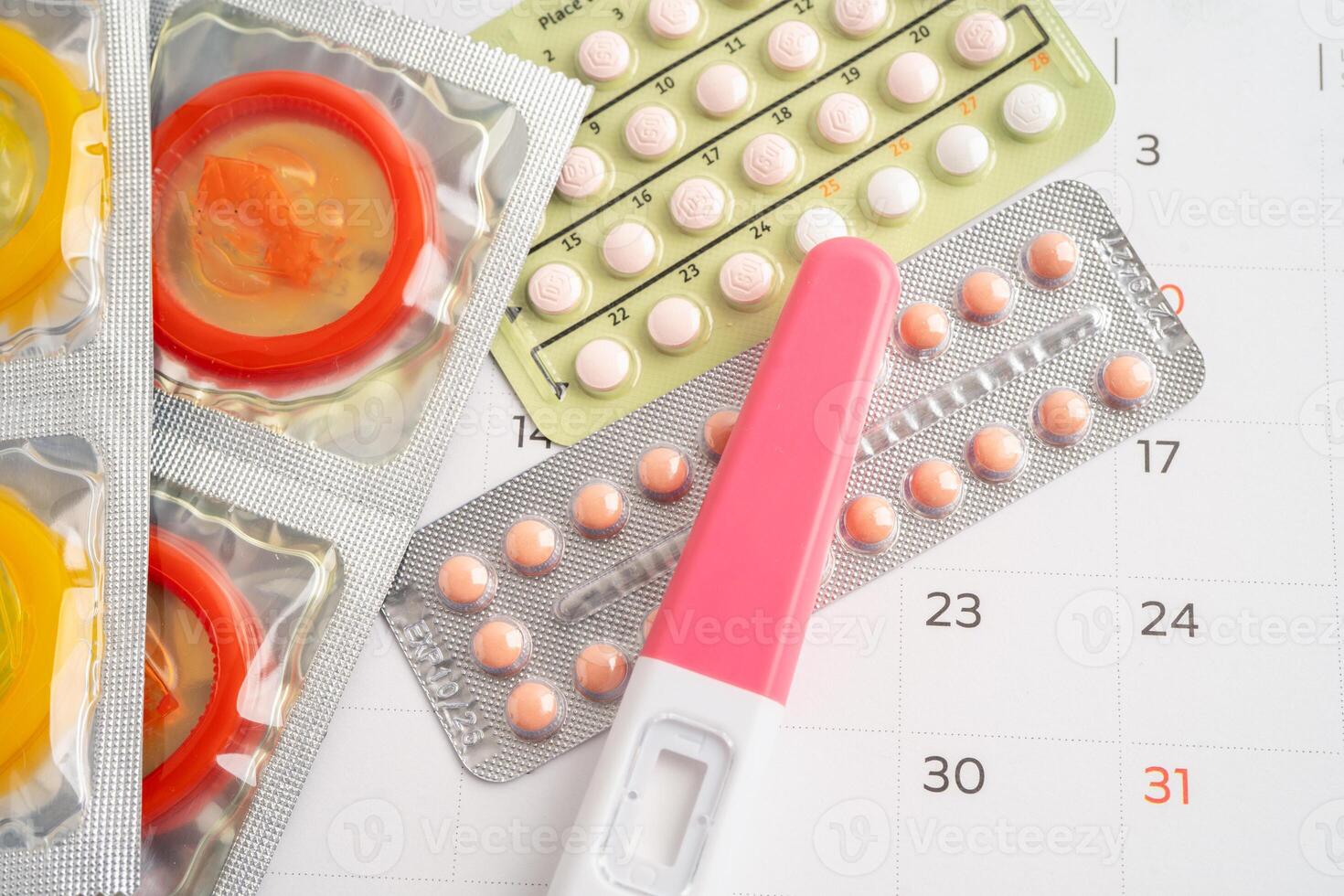Pregnancy test and birth control pills on calendar, contraception health and medicine. photo