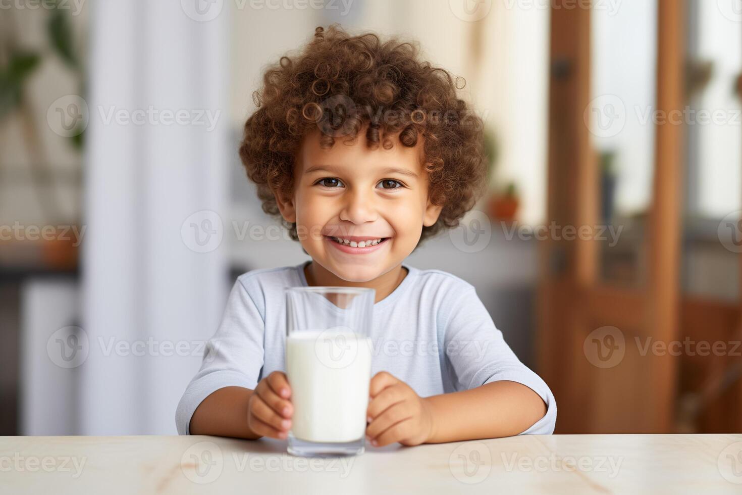 A handsome 4 year old smiling boy is sitting at the table with a glass of milk photo