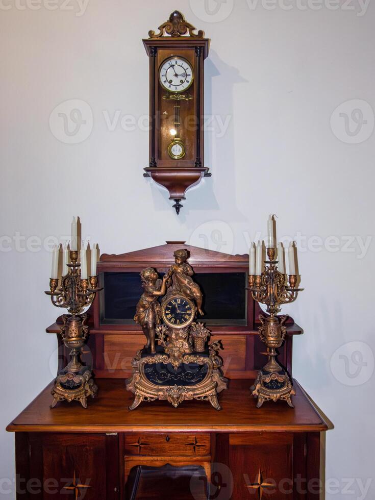 retro chest of drawers, clock, candlestick with candles in a classic interior photo