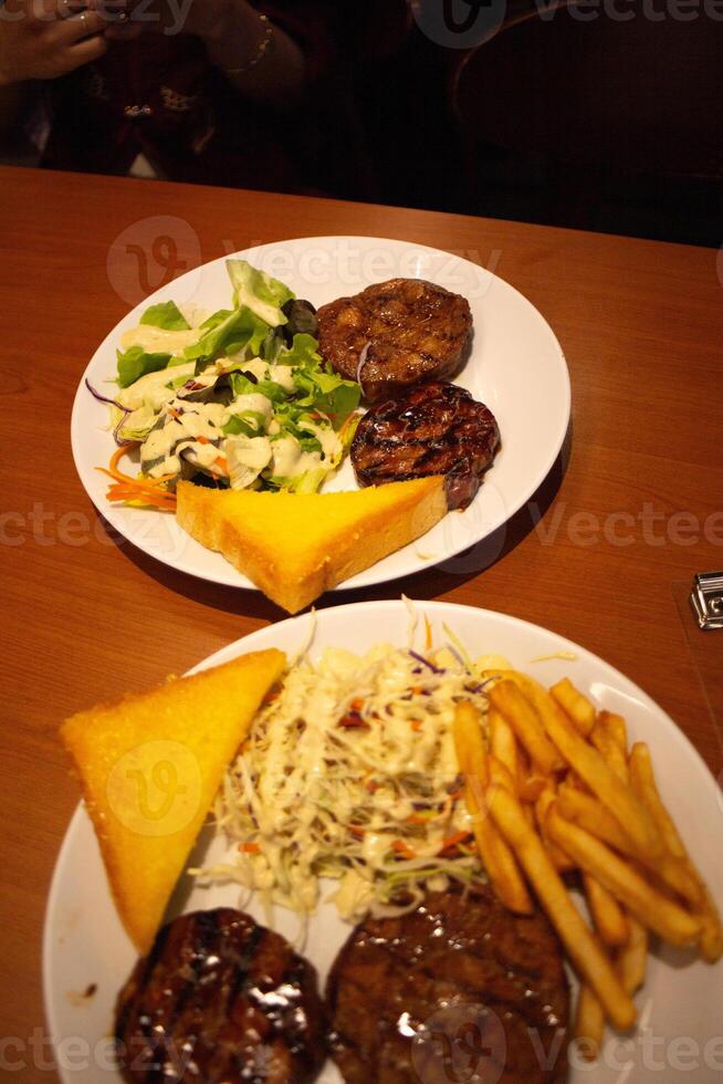 pork and chicken grilled Steak, toast, salad, dressing and frenchfries photo