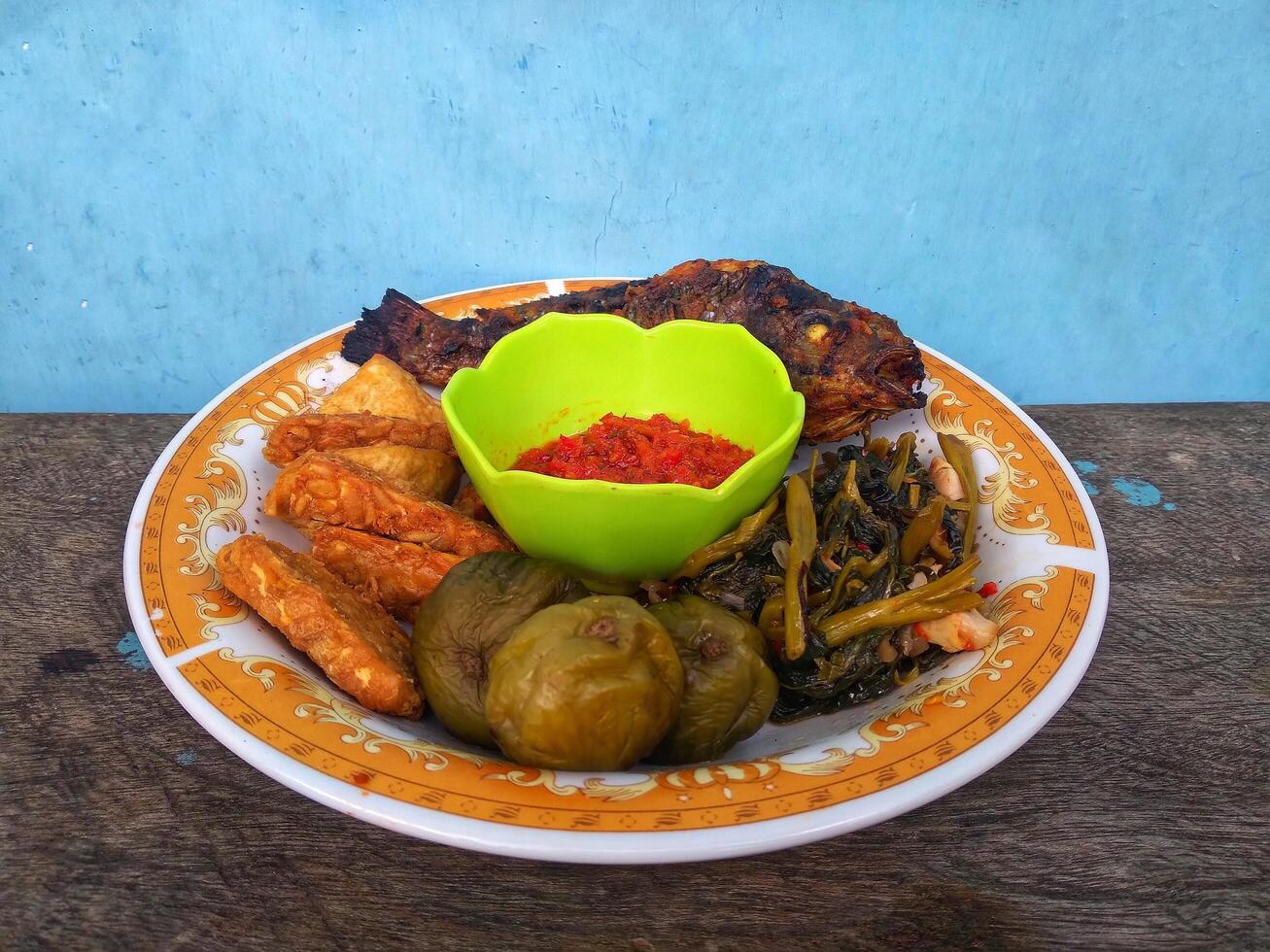 a plate of grilled fish, complete with chili sauce and fresh vegetables photo