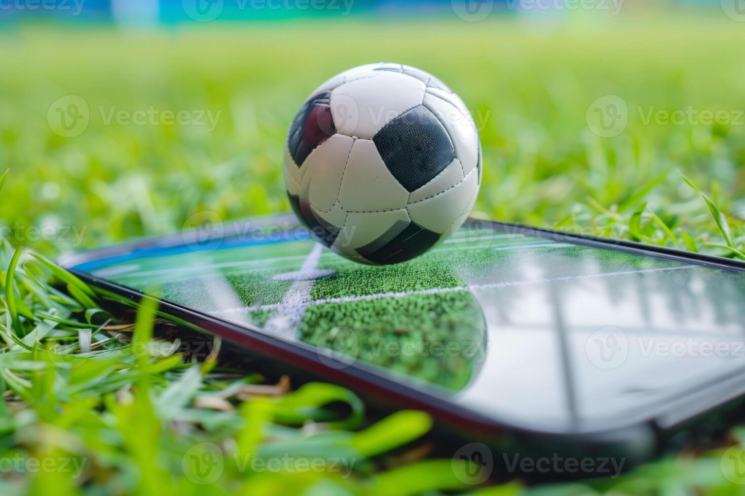 A soccer ball and smartphone on green grass, concept of real-time online soccer game broadcasting photo
