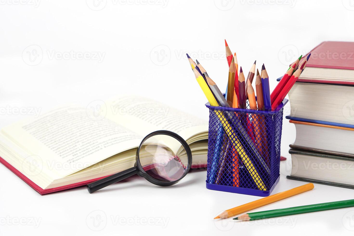 Focus crayon or colored pencils in box and magnifying glass, Blurred books lined up on white background. Learning, study and presentation concept. photo