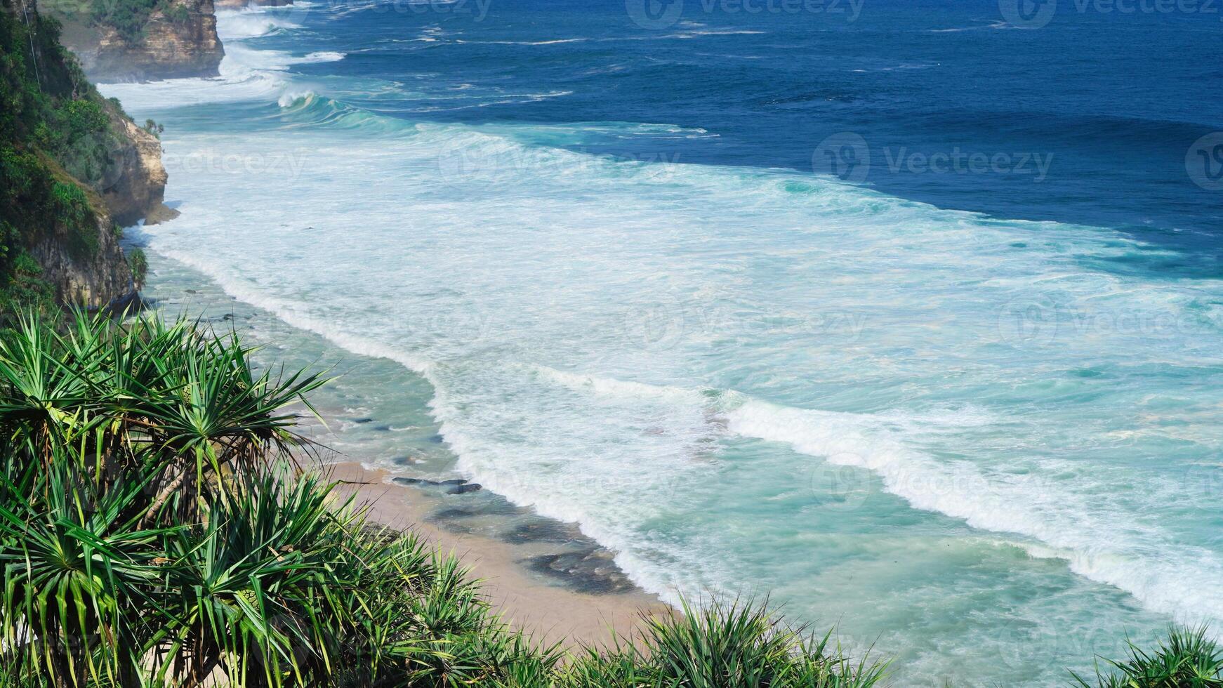 view of the beach from the top of the cliff, small waves and white foam photo