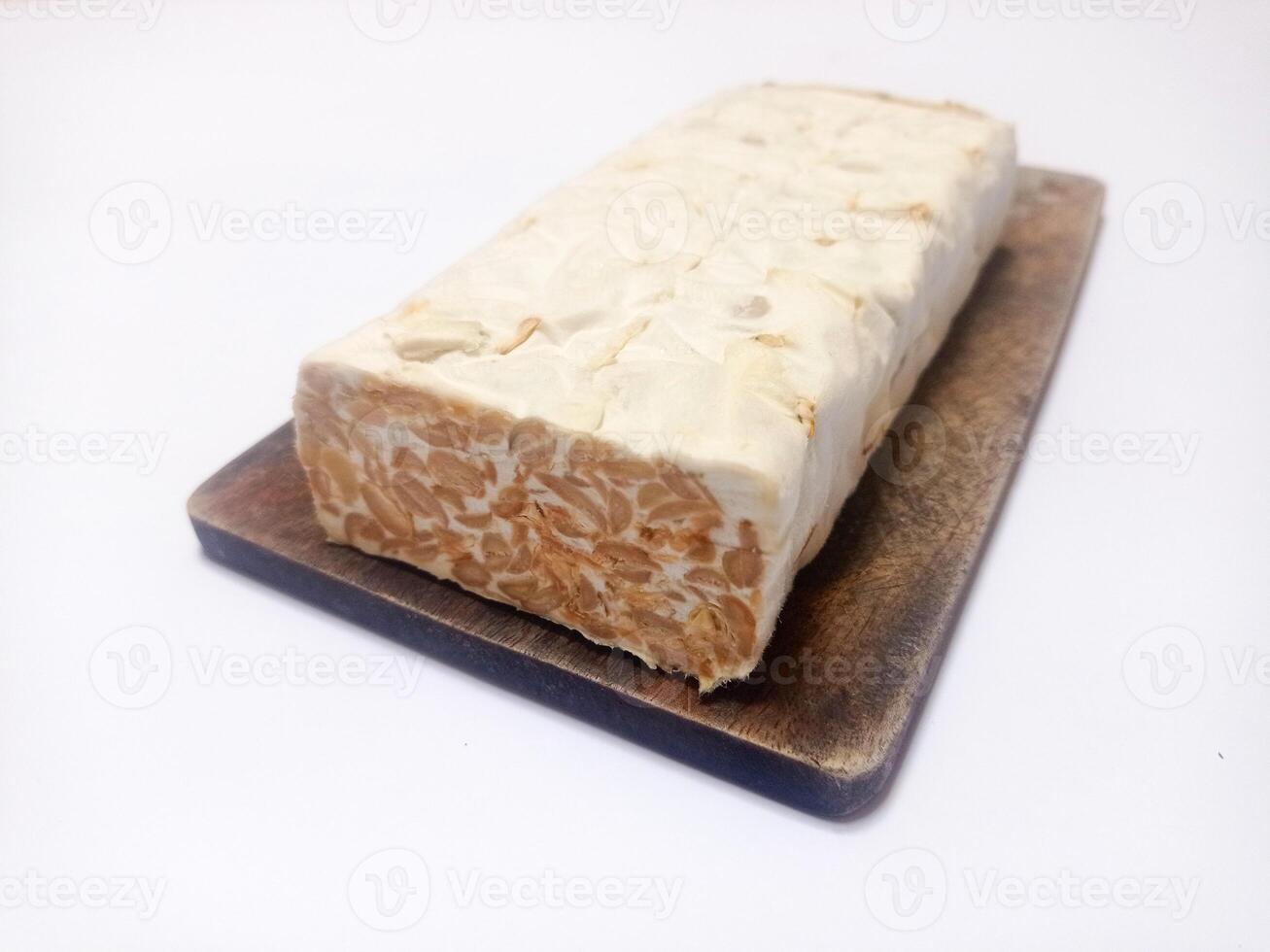 close up of raw tempeh on wooden cutting board isolated white background. Indonesian food tempeh photo