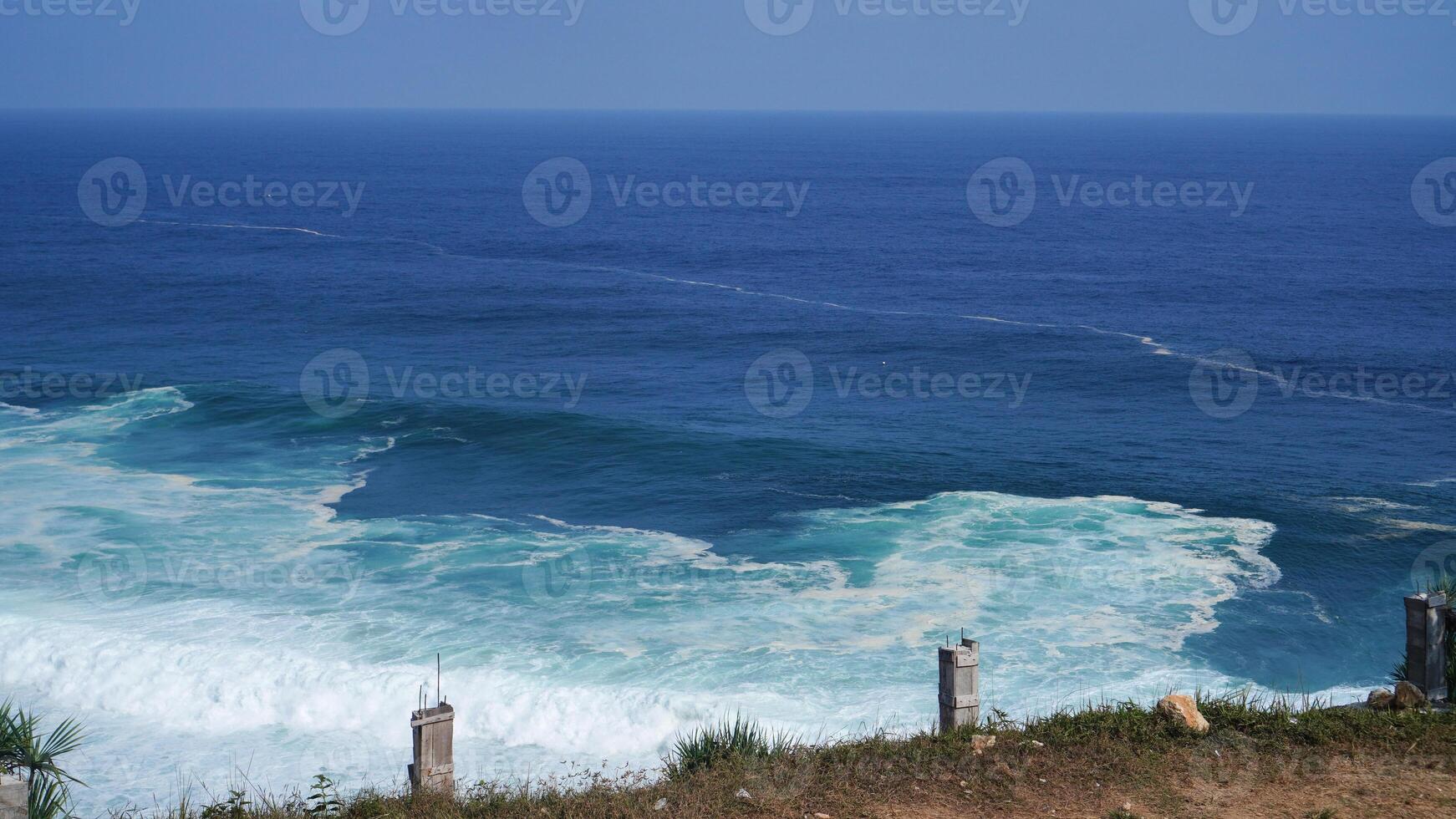 view of the beach from the top of the cliff, small waves and white foam photo