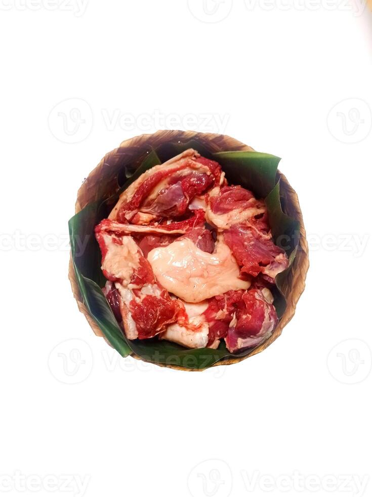 closeup of sacrificial goat meat in a bamboo container isolated on white background photo