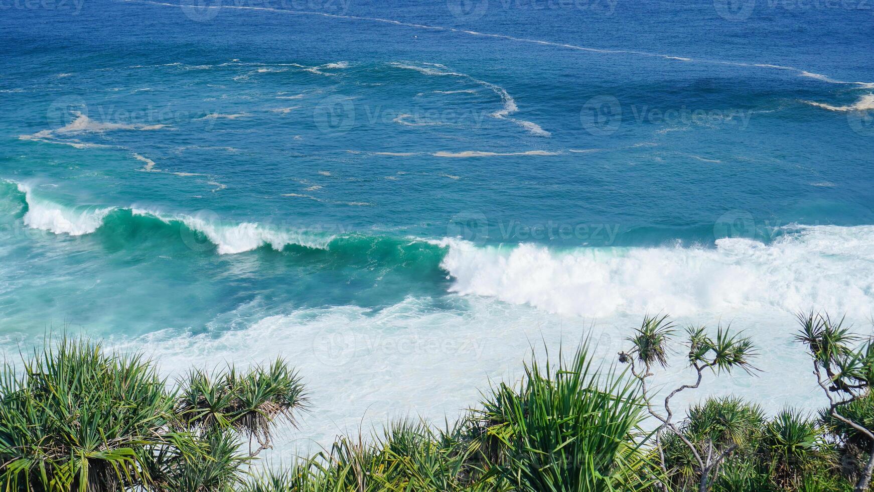 view of rolling waves and ocean from the top front view and surrounded by green plants. The beach is very beautiful. Idea as background, holiday, poster photo