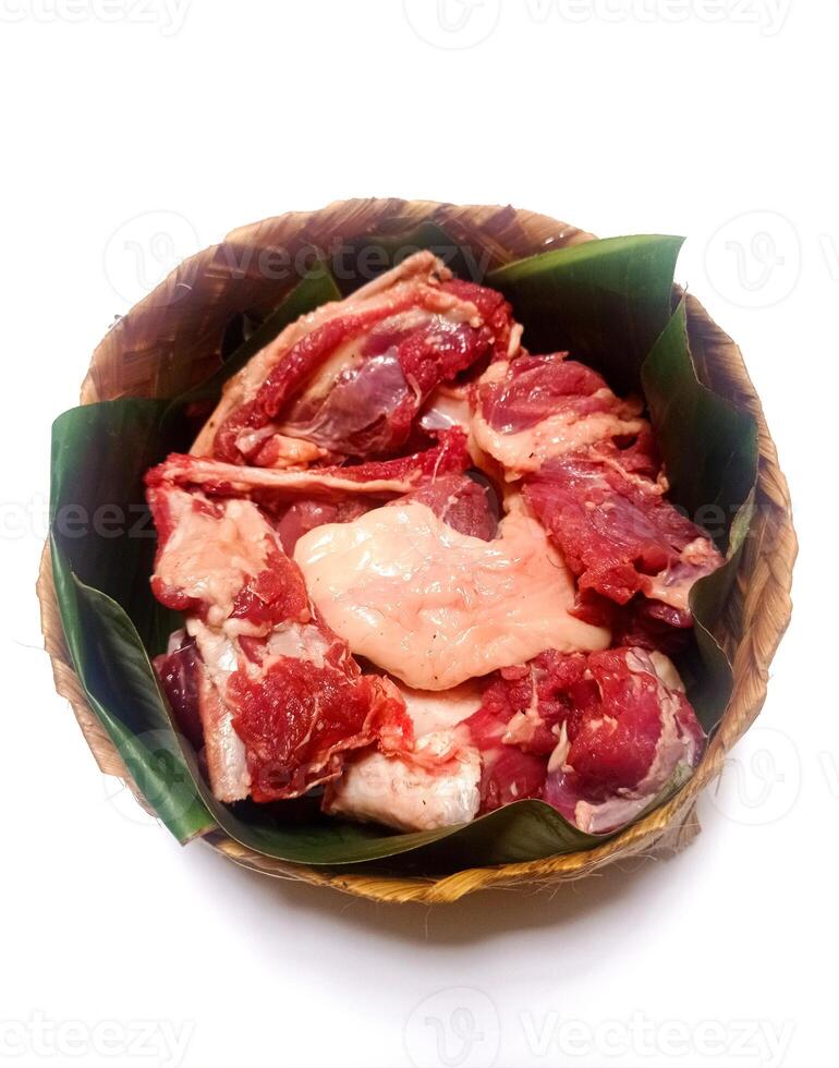 closeup of sacrificial goat meat in a bamboo container isolated on white background photo