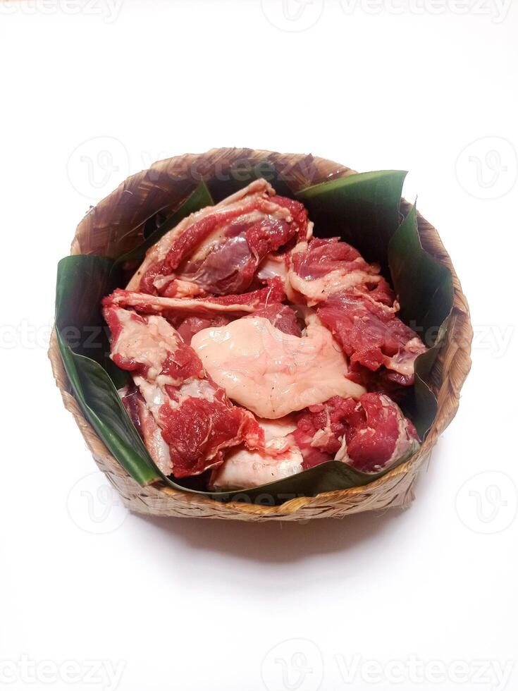 closeup of sacrificial goat meat in a bamboo container isolated on white background photo