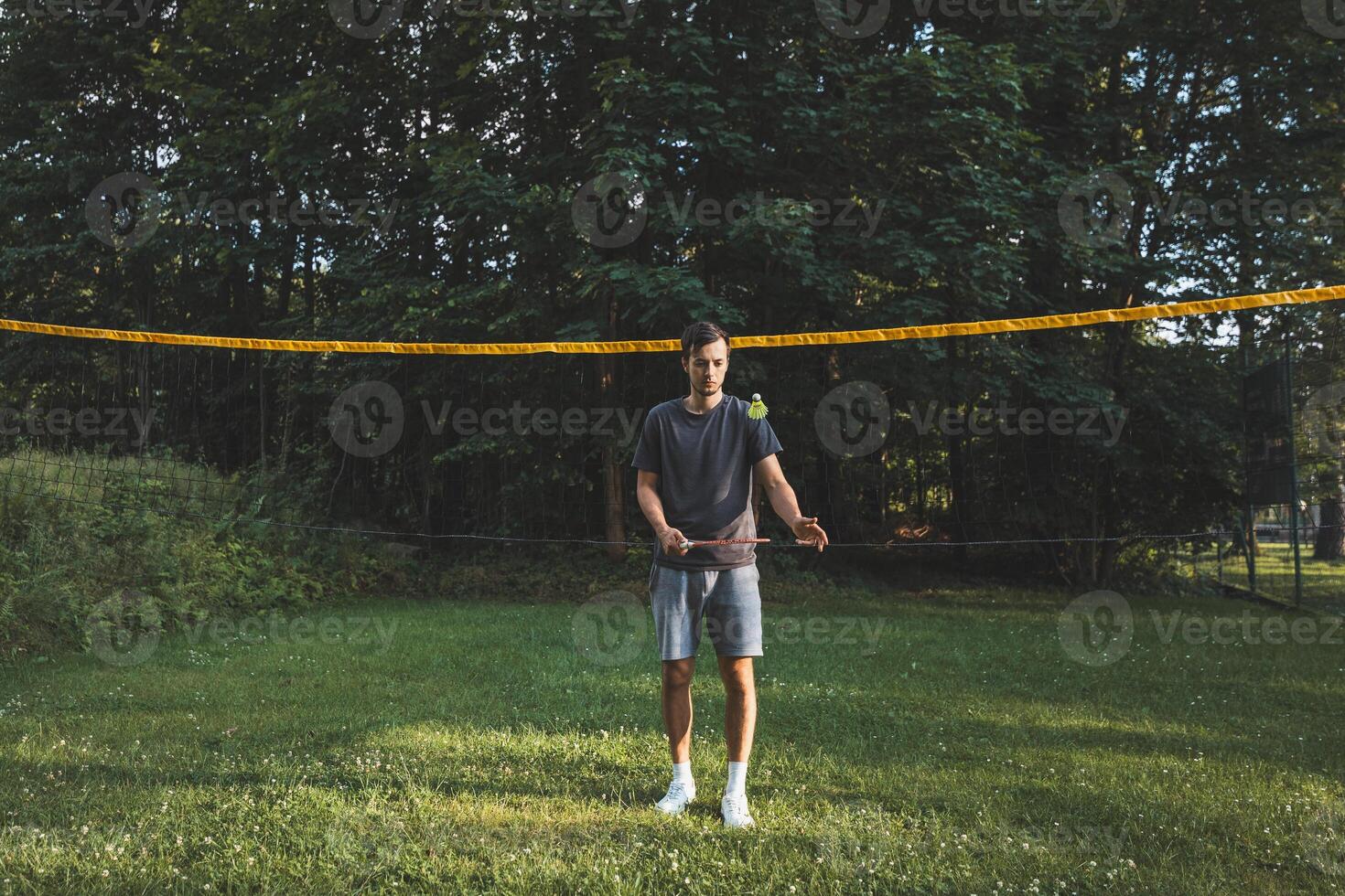 Black-haired badminton player practices his strokes on the grass court. Individual technique training. Amateur concept of the sport. The joy of the game photo