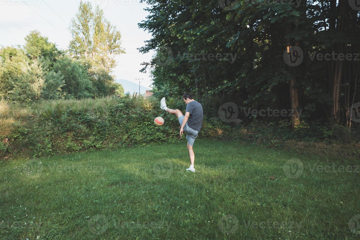 Black-haired athlete plays a friendly football match on the lawn. Amateur sport. Man playing with a ball. Dribbling practice. Sport lifestyle photo