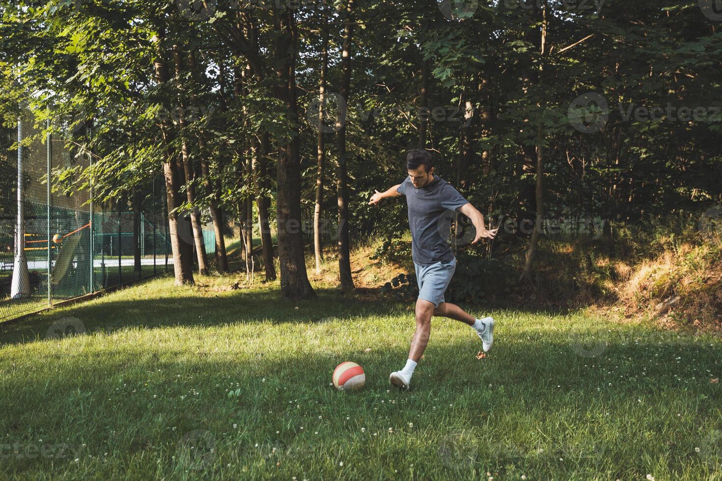 Black-haired athlete plays a friendly football match on the lawn. Amateur sport. Man playing with a ball. Dribbling practice. Sport lifestyle photo