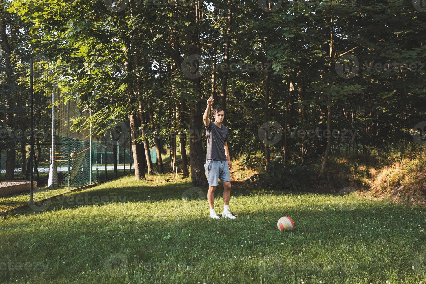 Black-haired athlete plays a friendly football match on the lawn. Amateur sport. Man playing with a ball. Dribbling practice. Sport lifestyle photo
