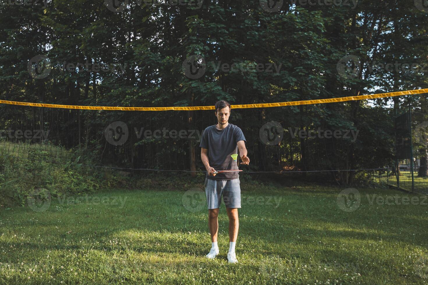 Black-haired badminton player practices his strokes on the grass court. Individual technique training. Amateur concept of the sport. The joy of the game photo
