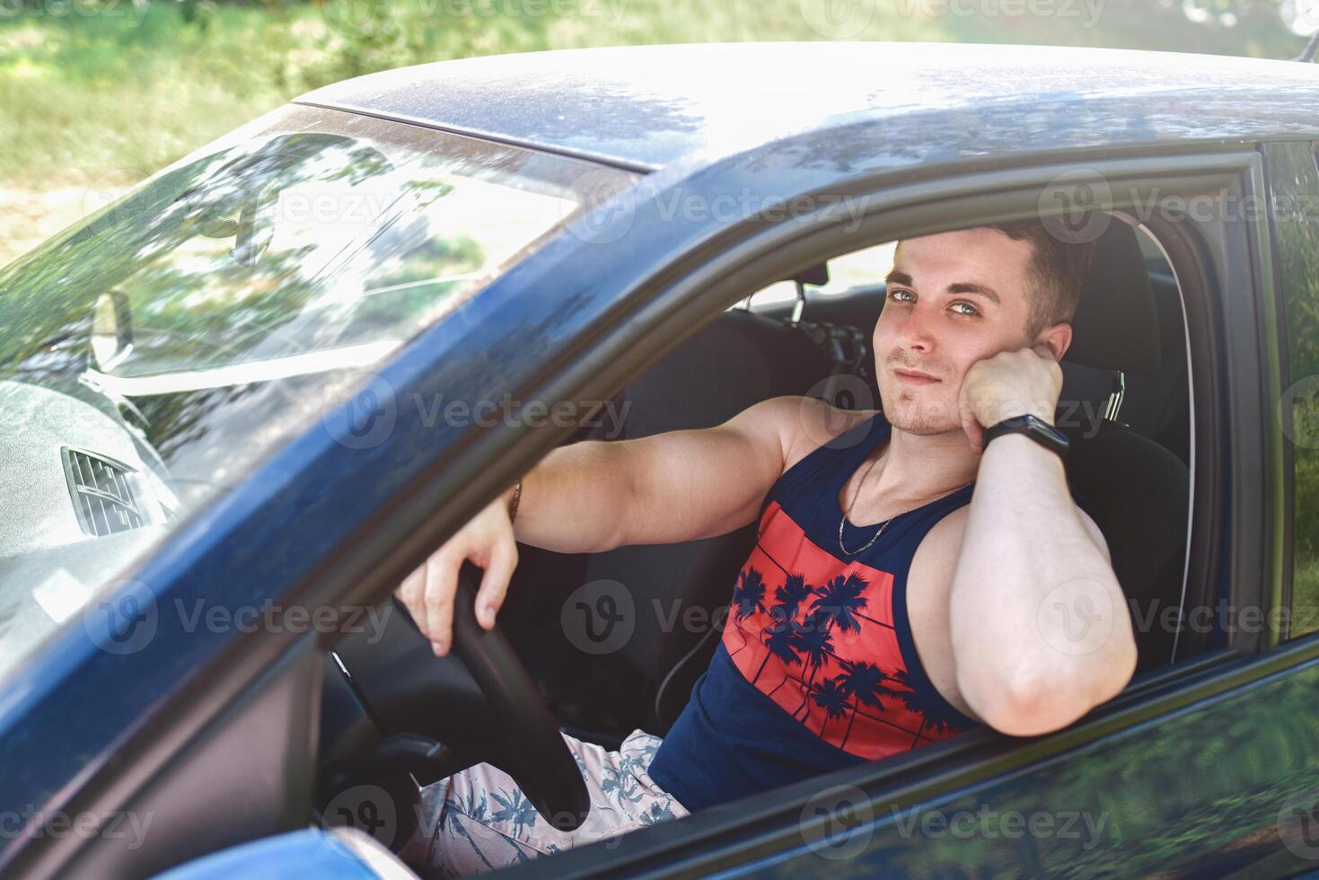 portrait of smiling young man sitting in a car and looking at the camera photo