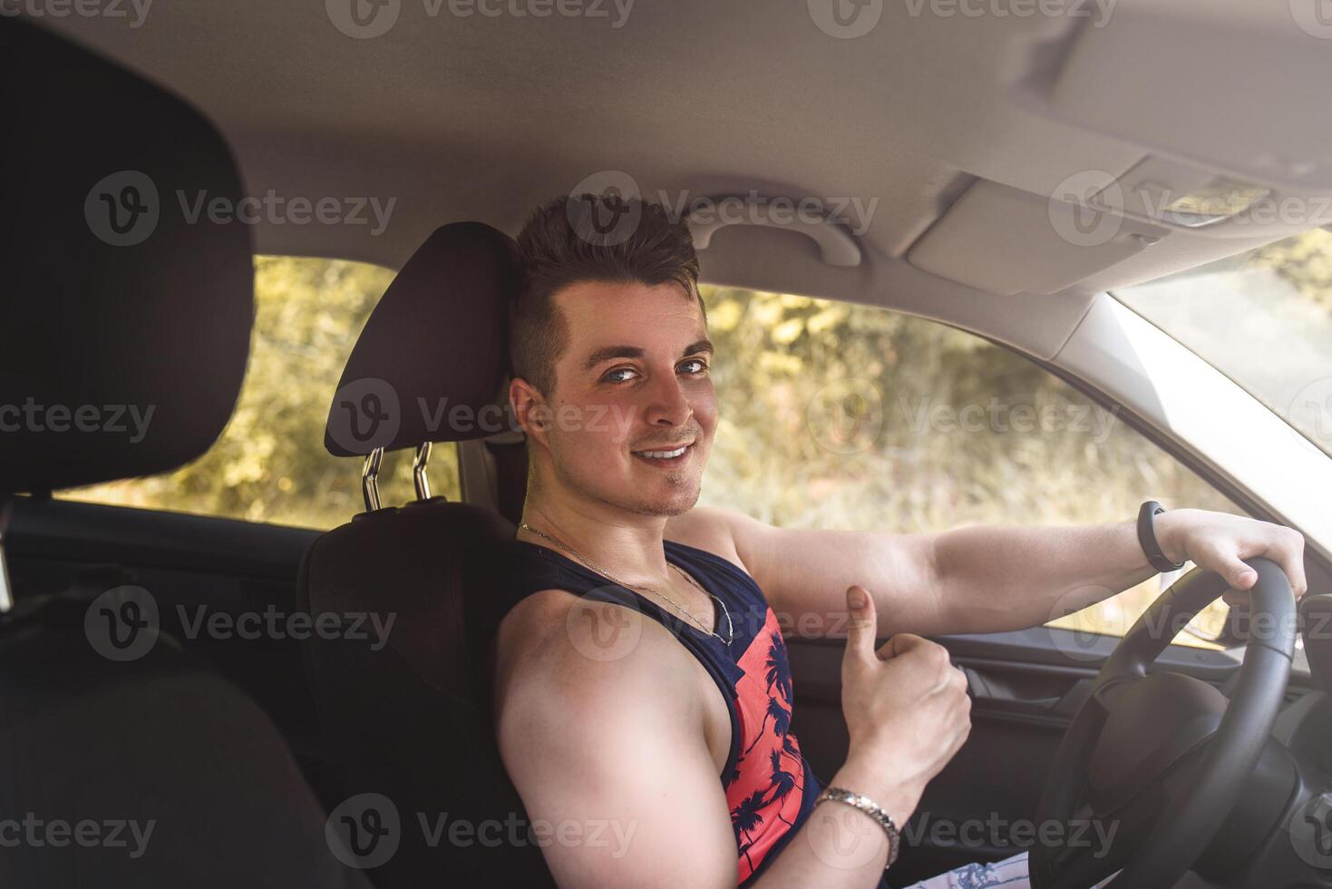 portrait of smiling young man sitting in a car and looking at the camera photo