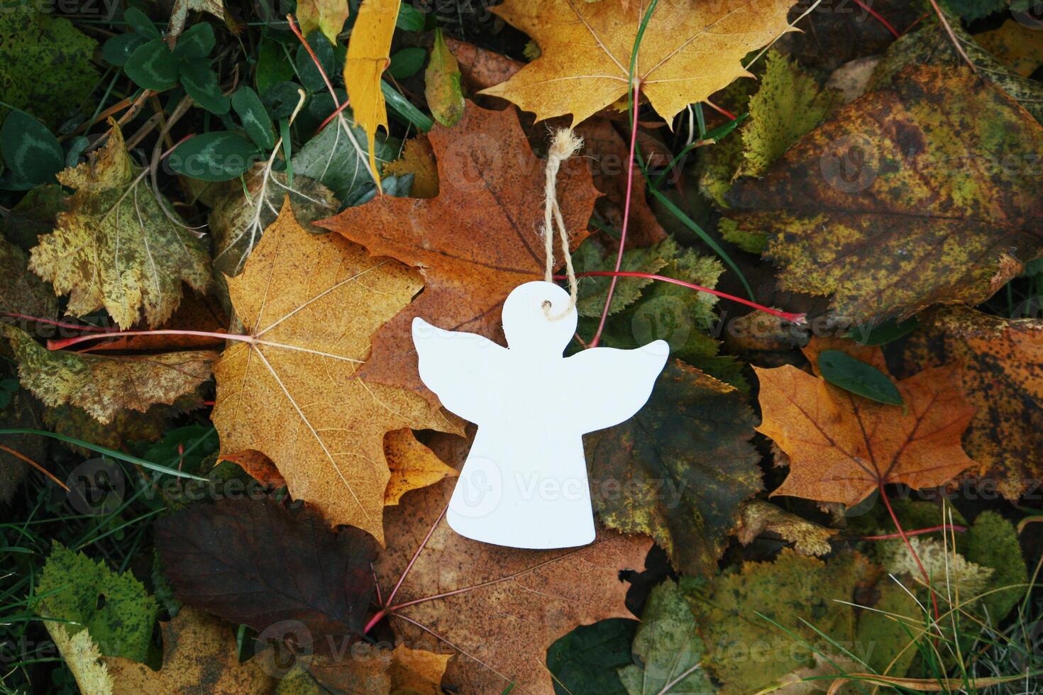 Wooden decoration angel white figure on fall leaves background photo