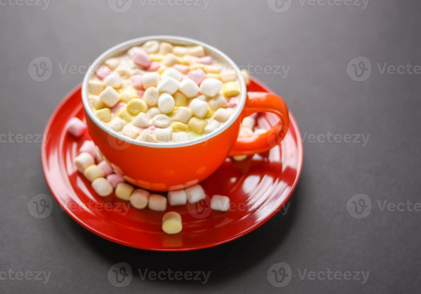 Cocoa drink with colorful small marshmallows on red background photo