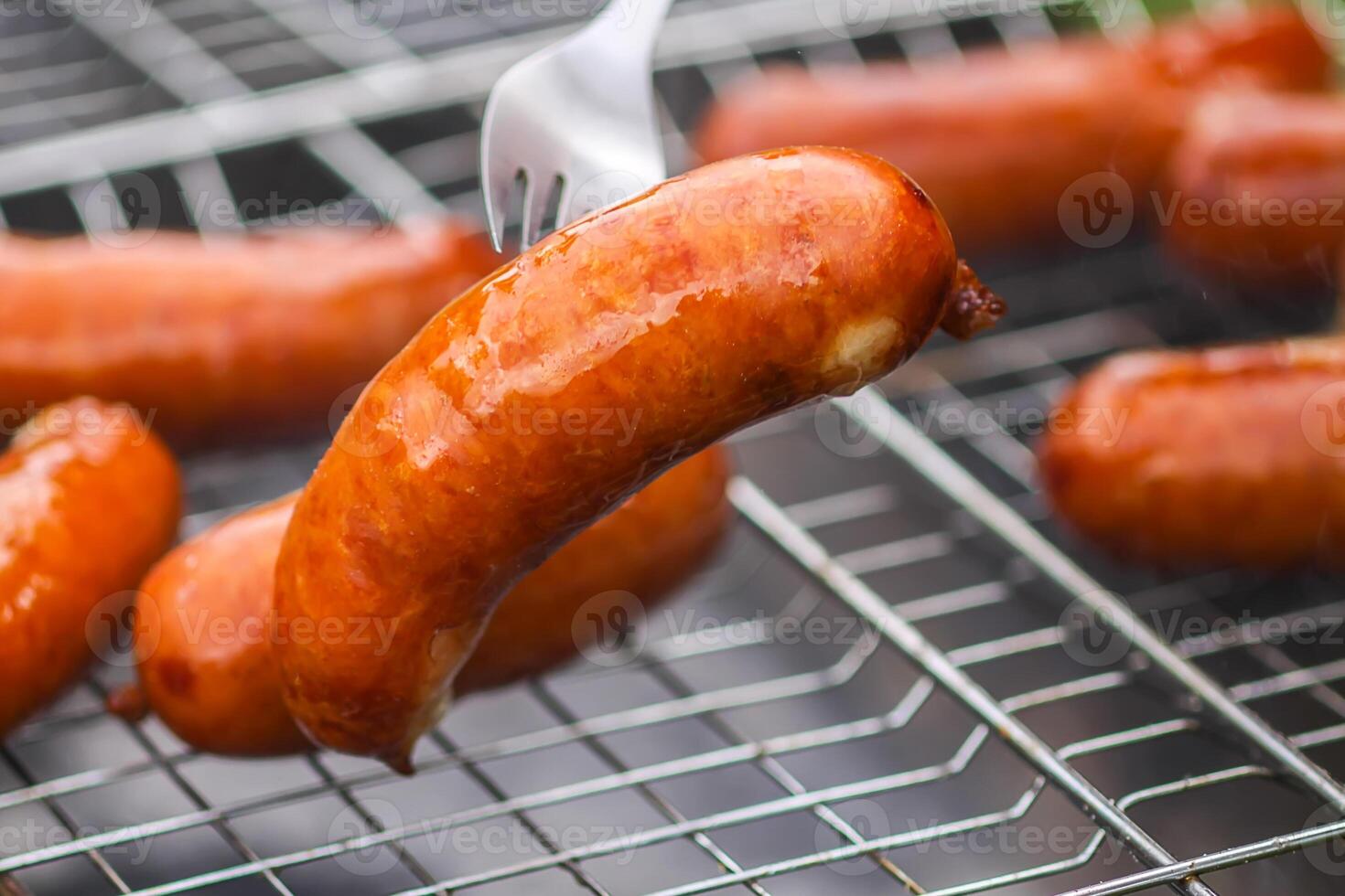 Tasty grilled sausages. Frying on brazier outdoors in the countryside at summer. photo