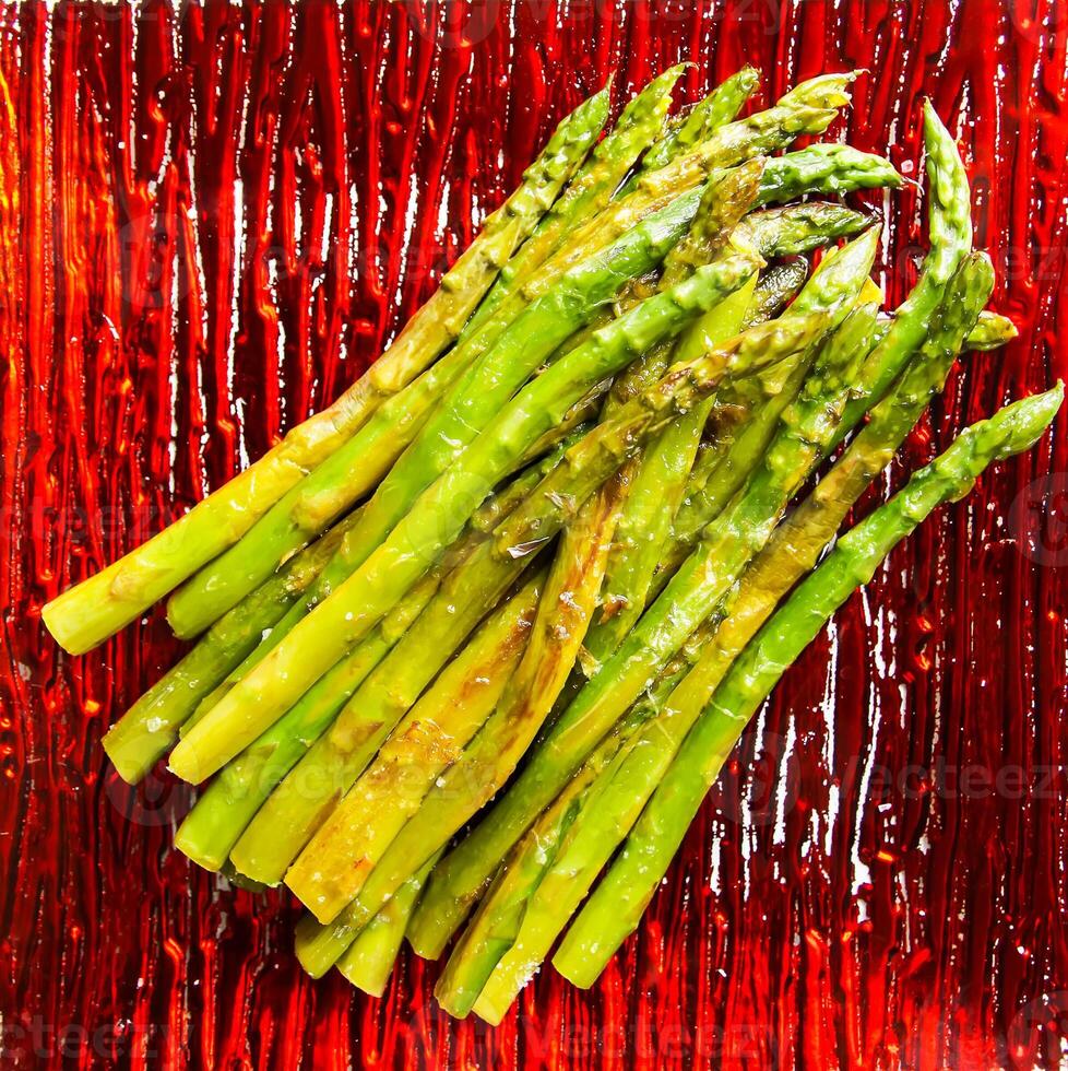 Green grilled asparagus on a red plate photo