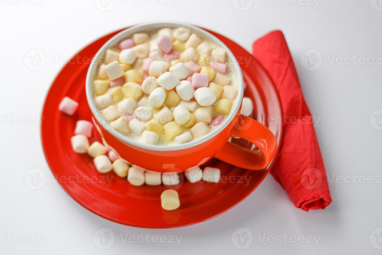 Cocoa drink with colorful small marshmallows on red background photo
