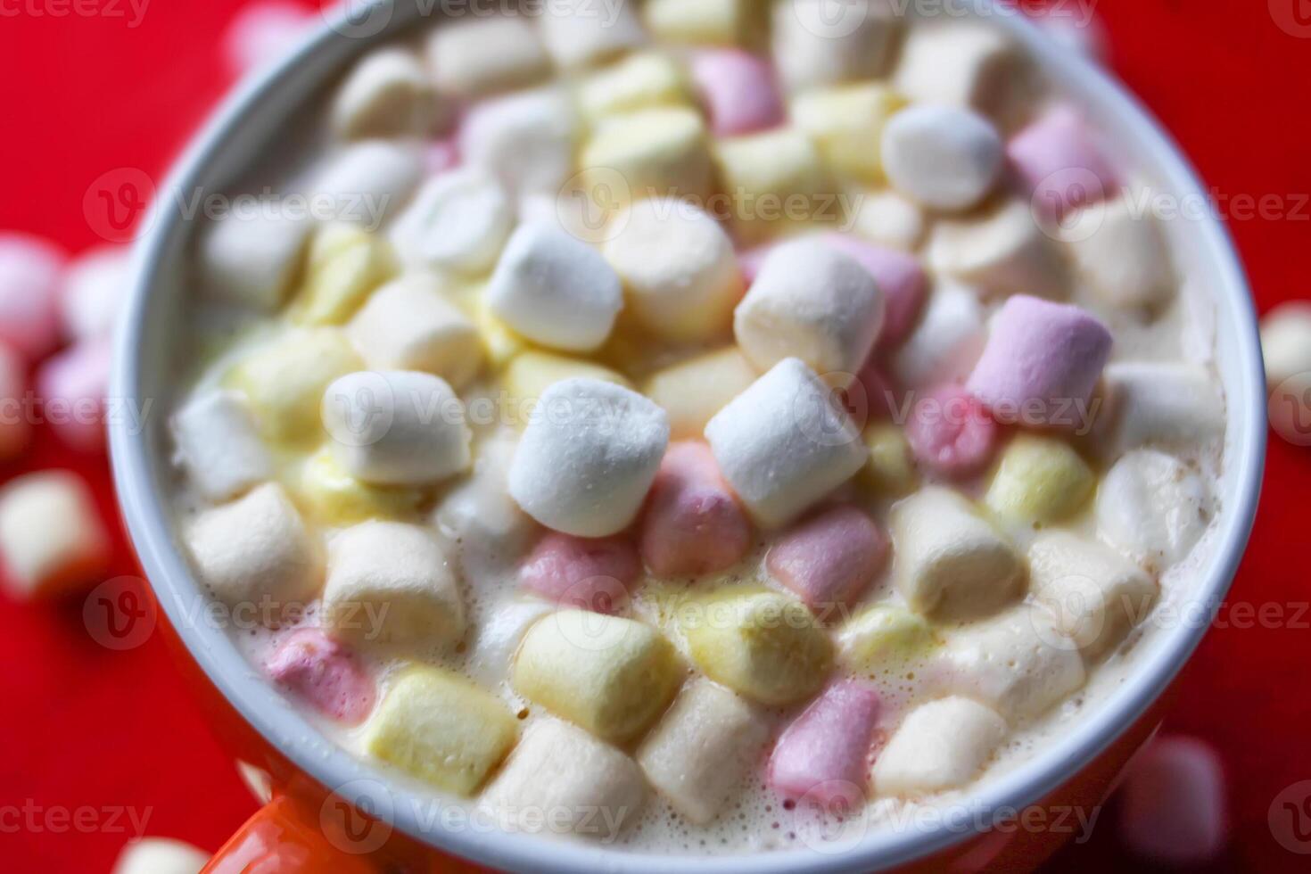 Cocoa drink with colorful small marshmallows on red background photo