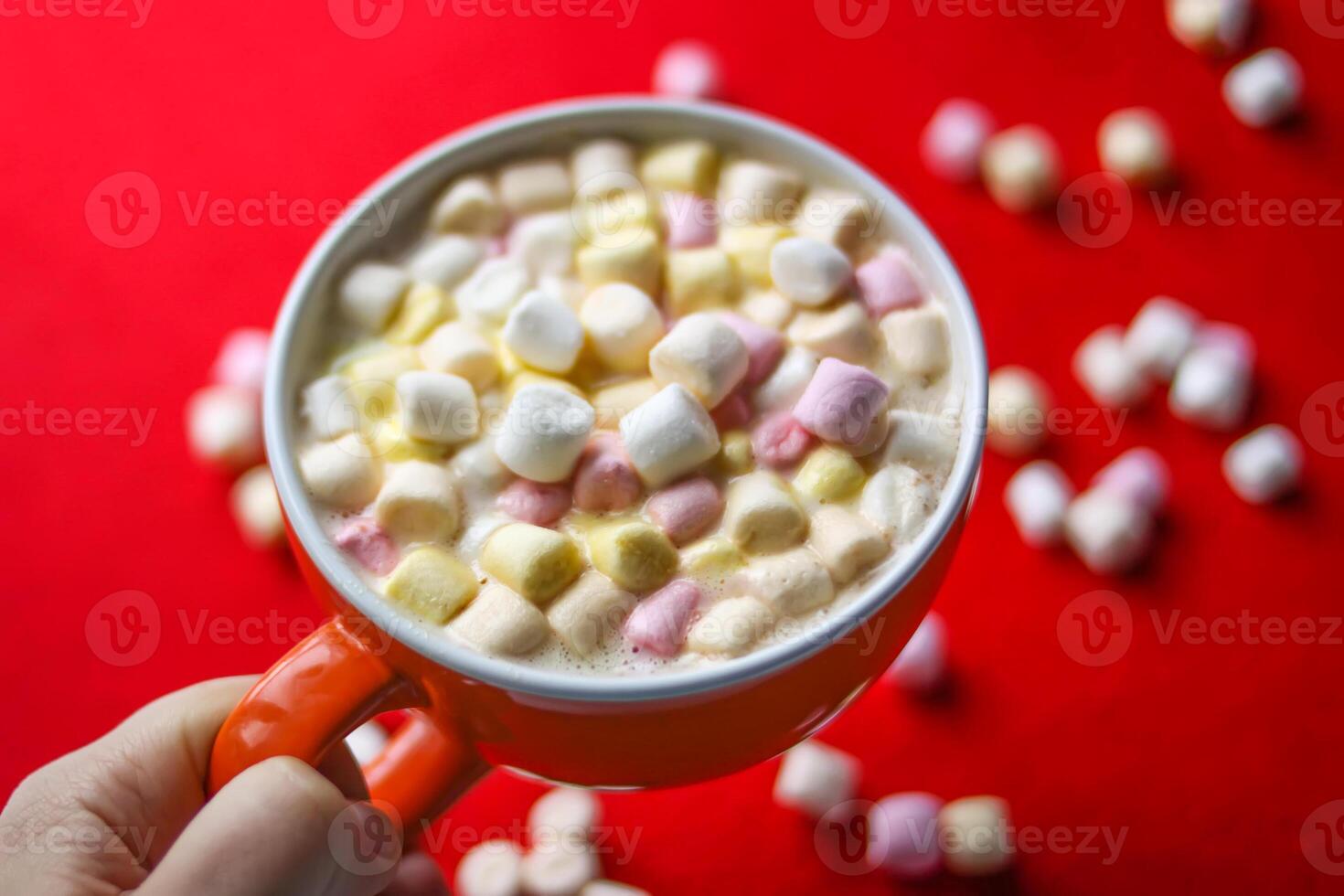 Cocoa drink with colorful small marshmallows on red background photo