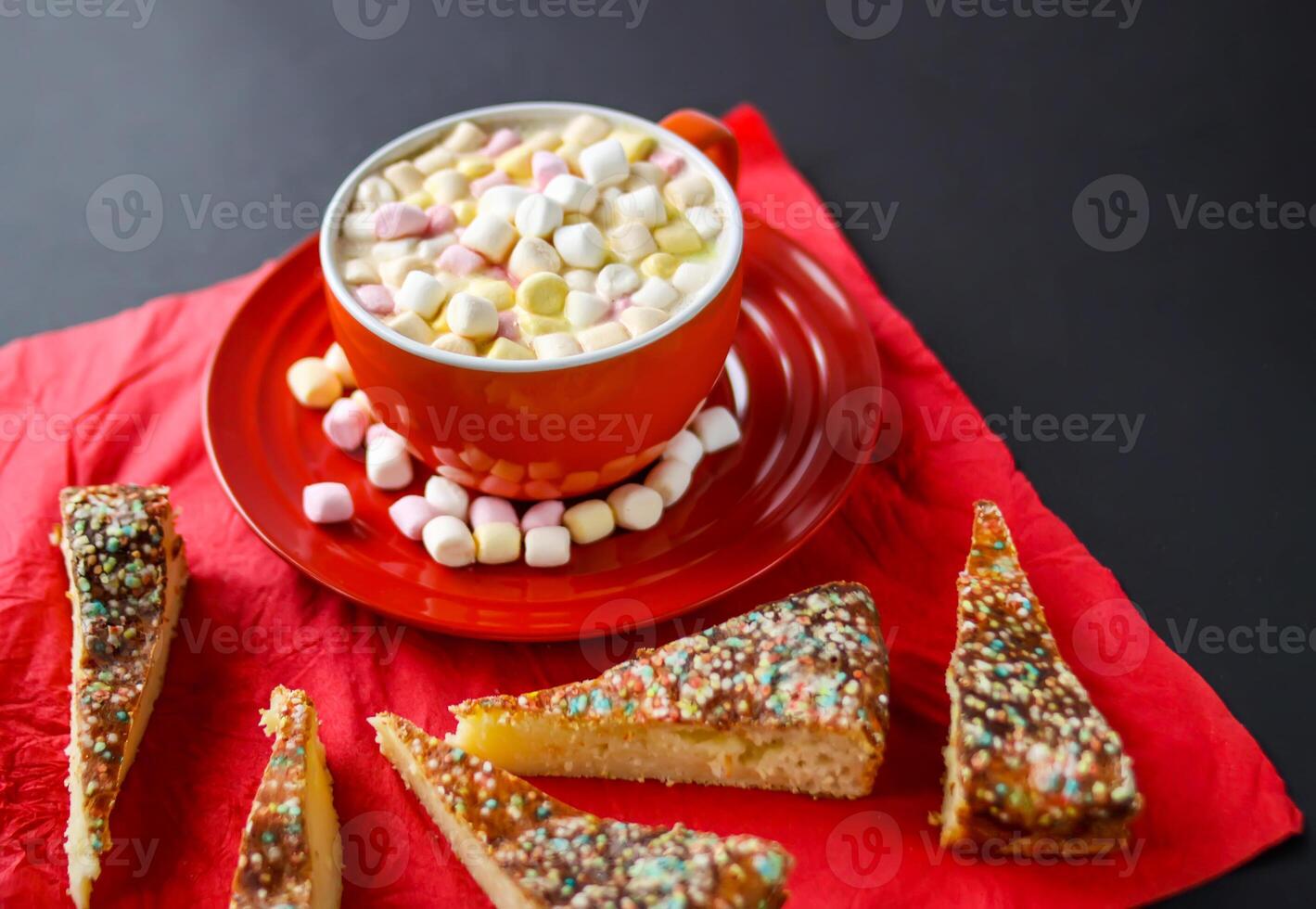 Cocoa drink with colorful small marshmallows on red background photo