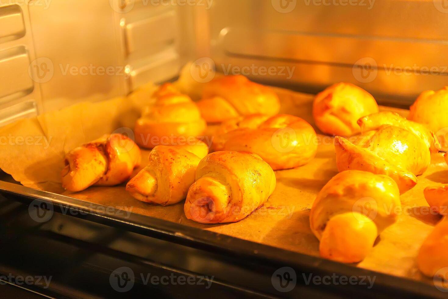 Homemade sweet cinnamon roll baking on a sheet in oven photo