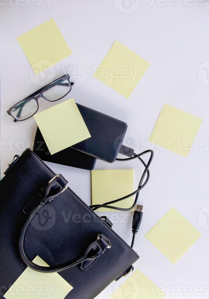Composition with black bag, external hard disks, colorful paper empty stickers and glasses. photo