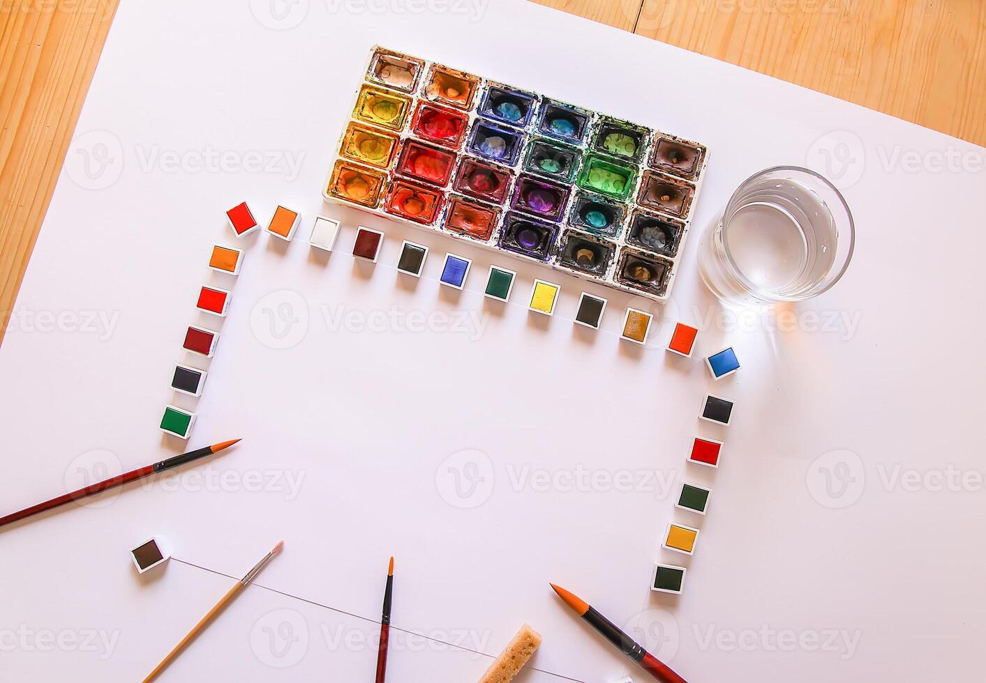 Watercolor paints, brushes, water in glass and paper on white background. Flat lay, top view photo