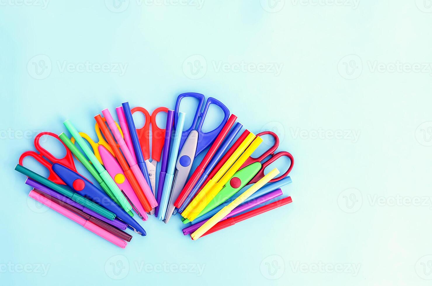 School supplies. Back to School design elements. Colorful markers and scissors on light blue background. photo