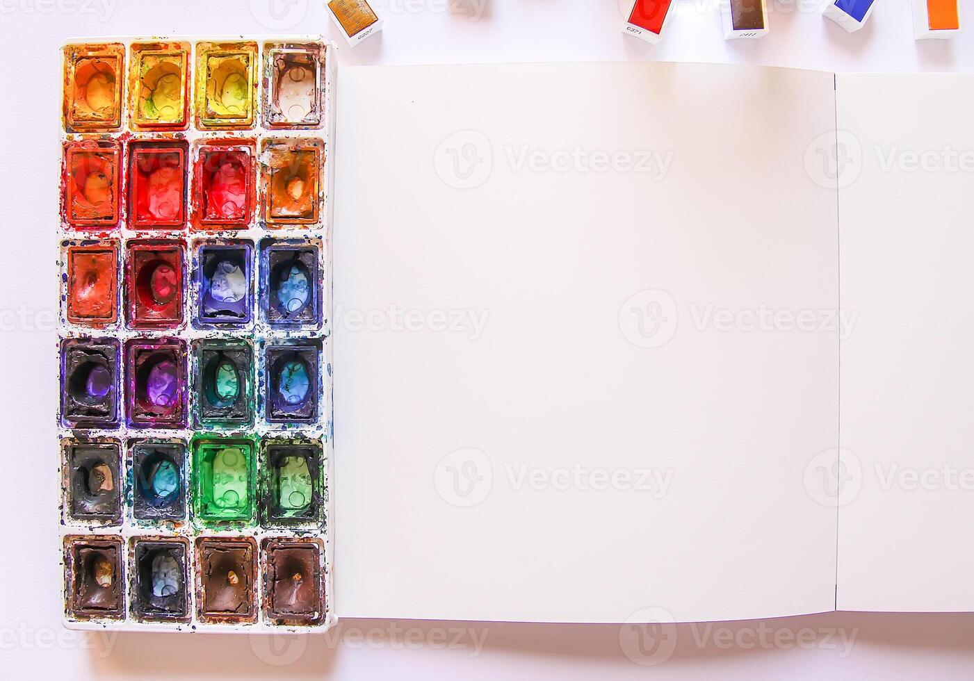Watercolor paints, brushes and paper on white background. Flat lay, top view photo