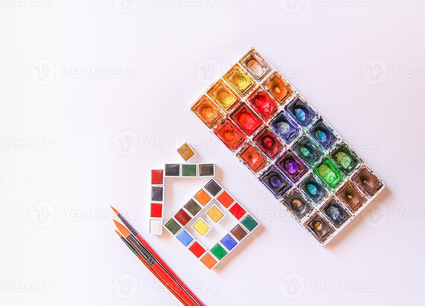 Watercolor paints, brushes and paper on white background. Flat lay, top view photo