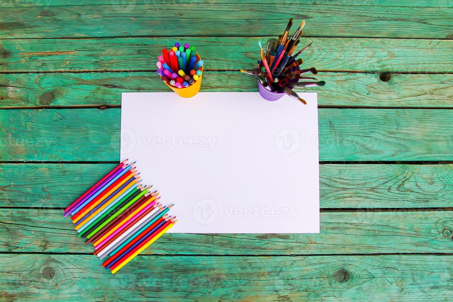 White paper sheet and school supplies on wooden aged background. photo