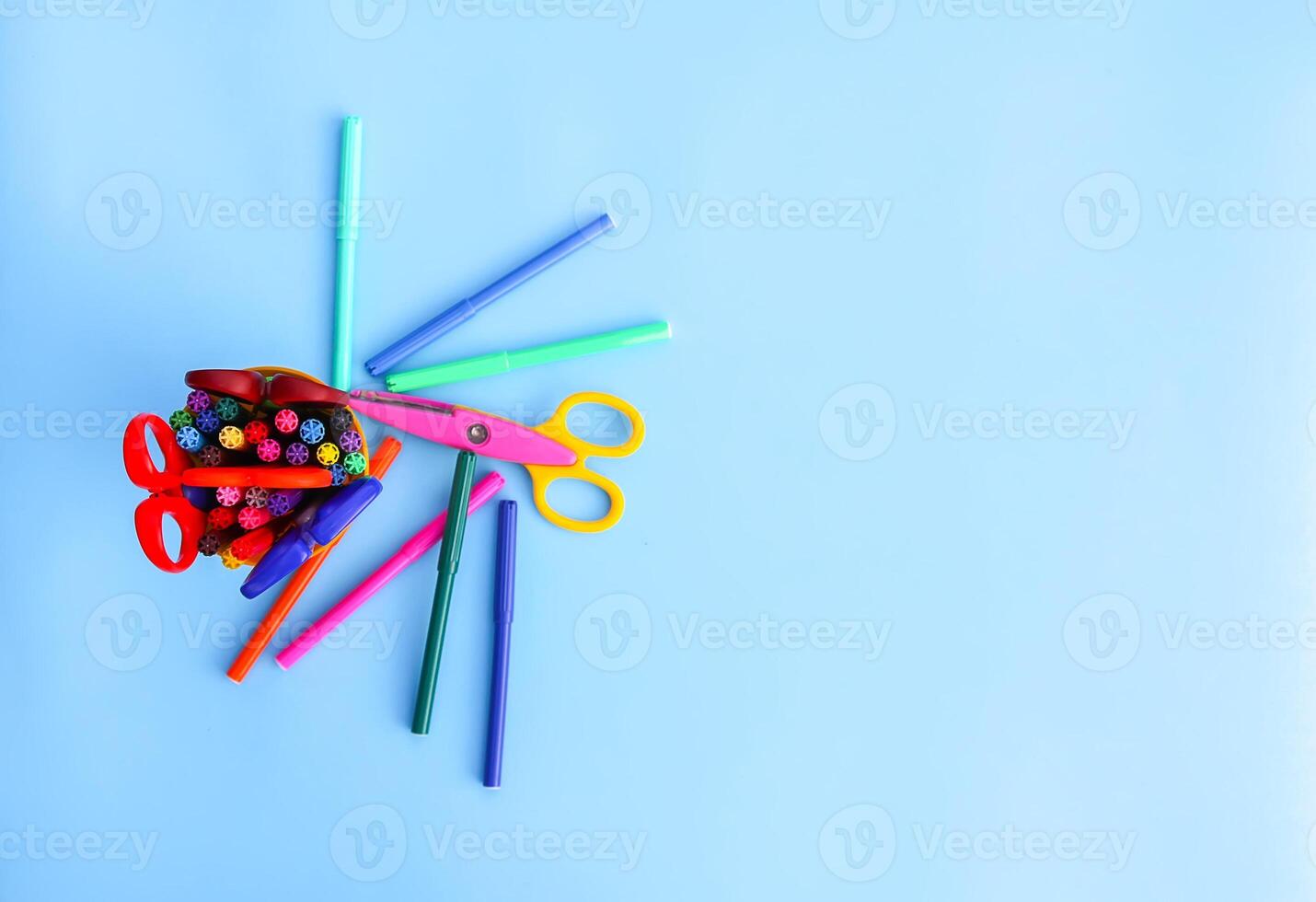 School supplies. Back to School design elements. Colorful markers and scissors on light blue background. photo