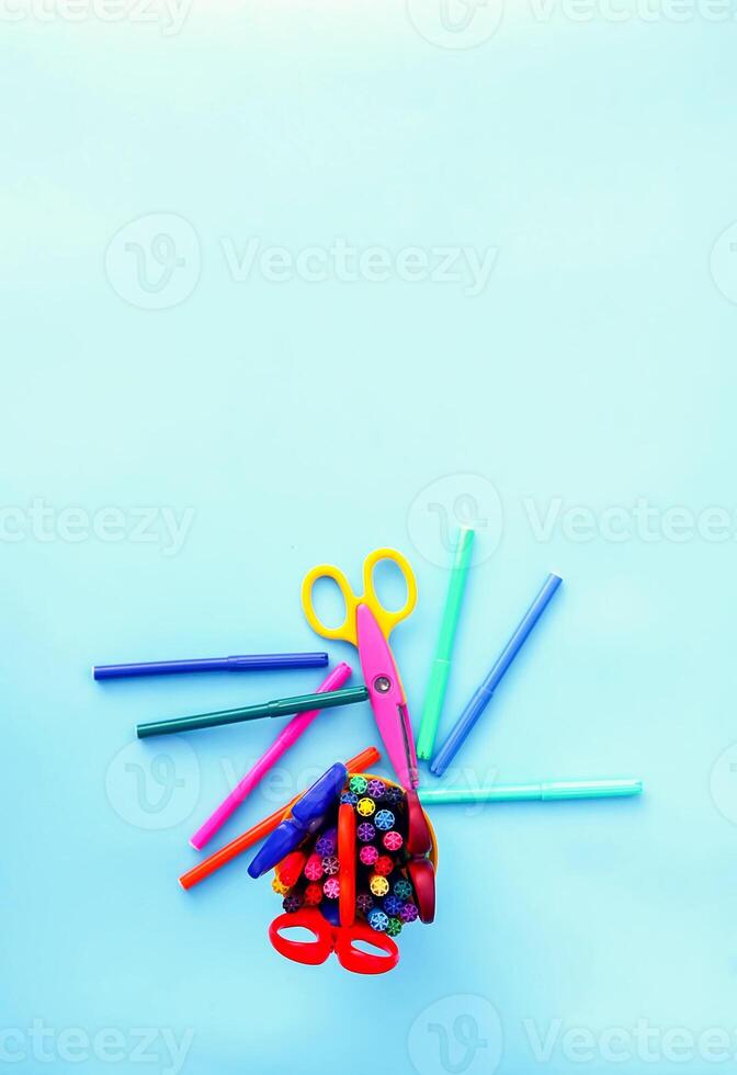 School supplies. Back to School design elements. Colorful markers and scissors on light blue background. photo