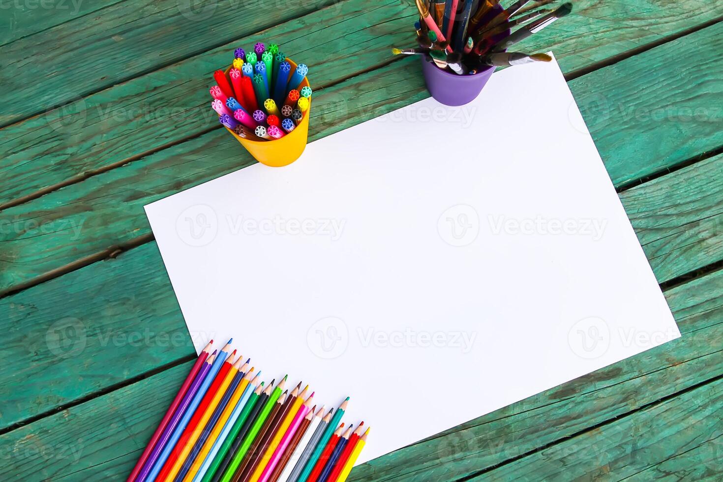 White paper sheet and school supplies on wooden aged background. photo
