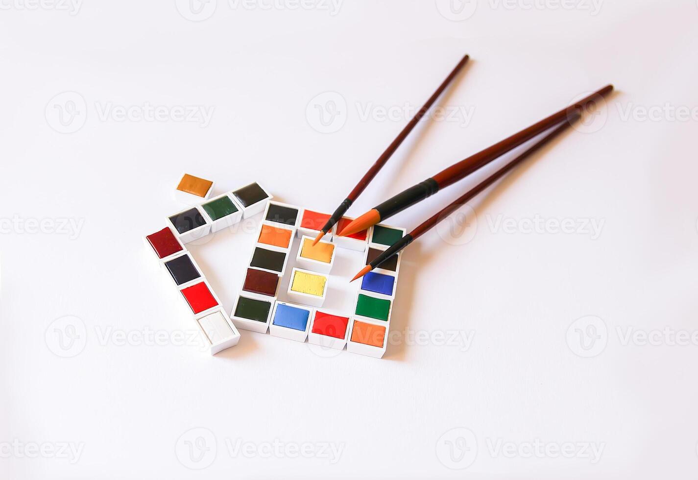 Watercolor paints in the shape of a house and paintbrushes on white background. Painting tools. Flat lay, top view photo