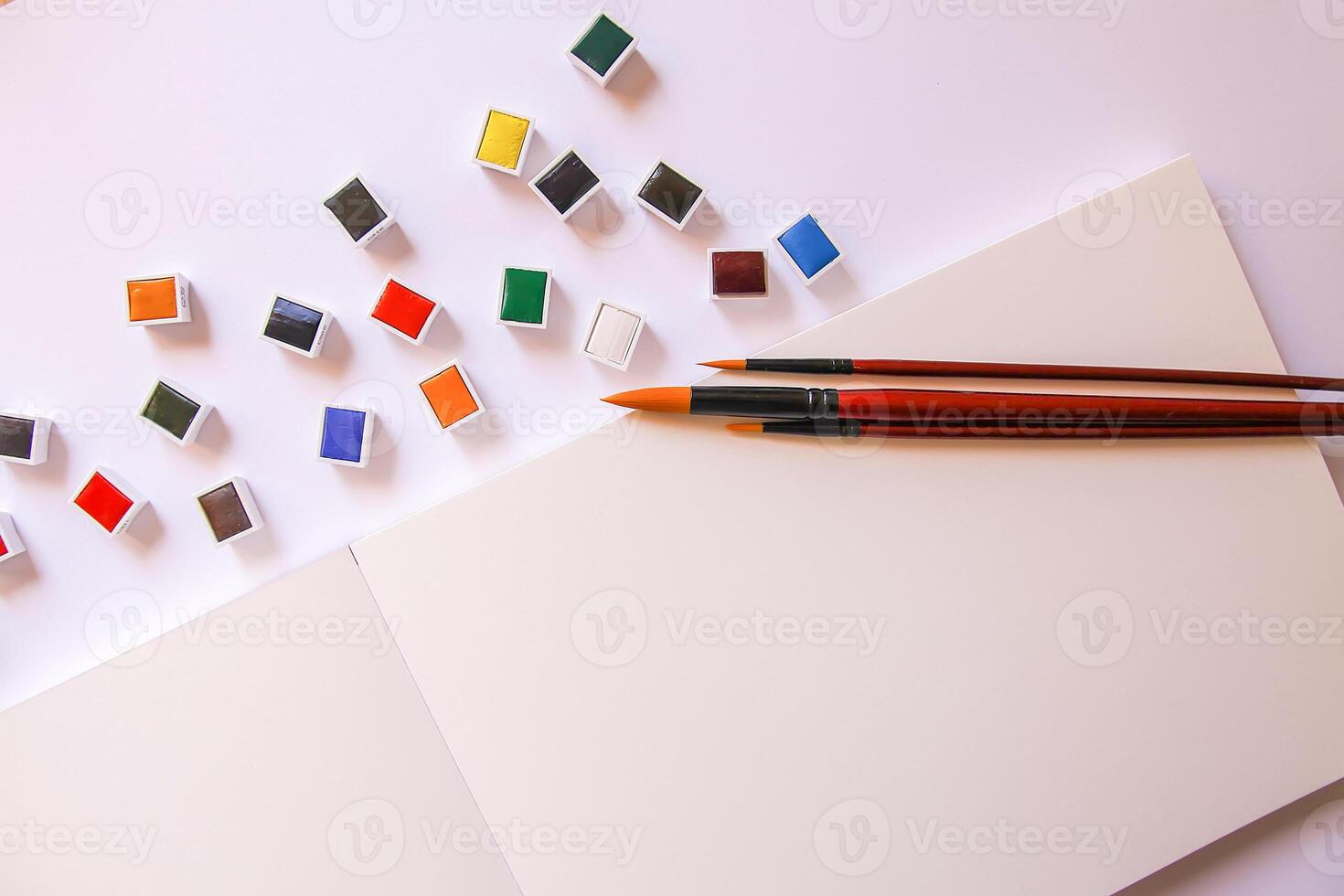 Watercolor paints, brushes and paper on white background. Flat lay, top view photo