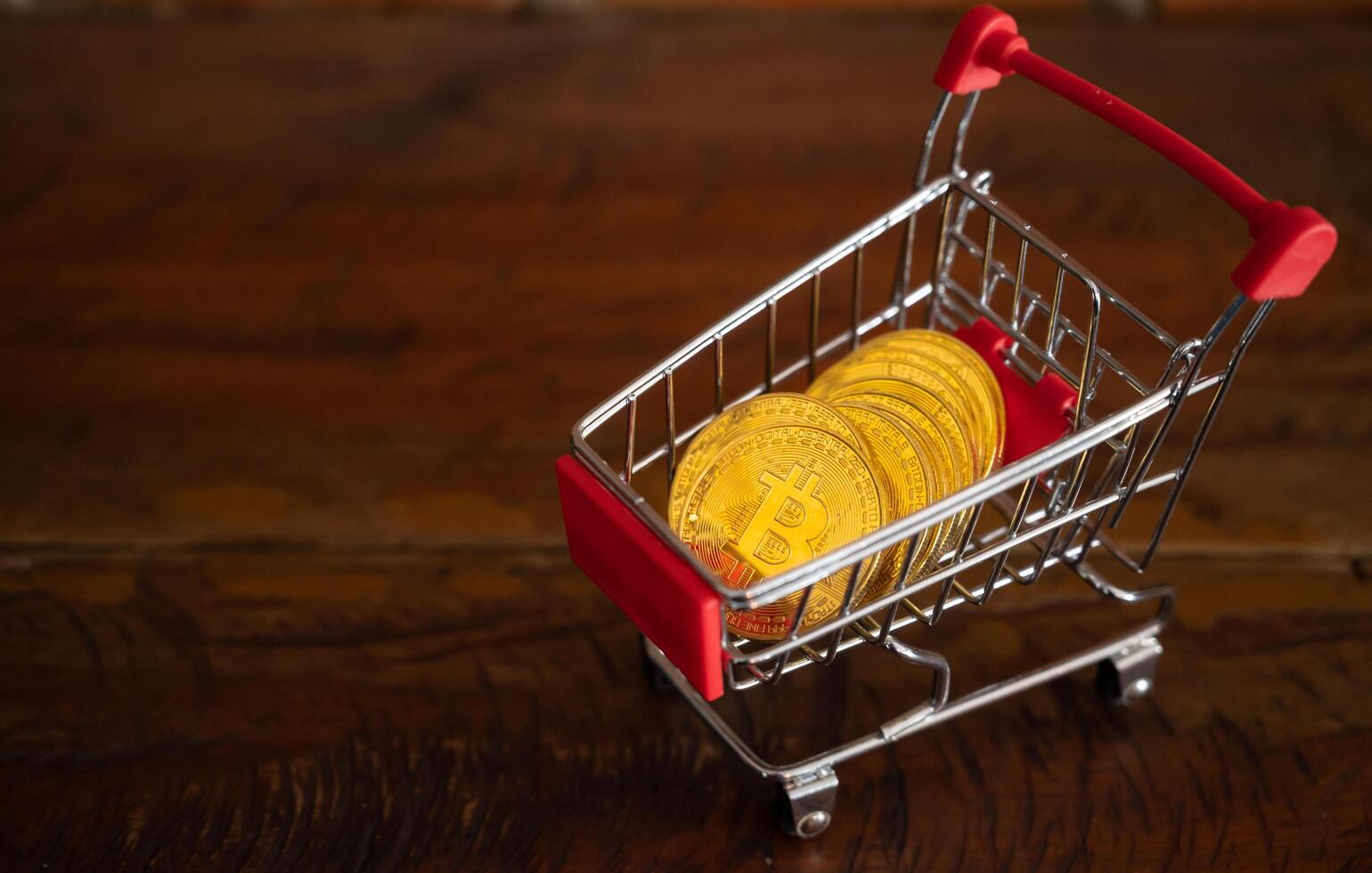 Bitcoin token in a trolley on wooden table. Bitcoin is one of the popular cryptocurrency, a virtual currency or a digital currency. photo