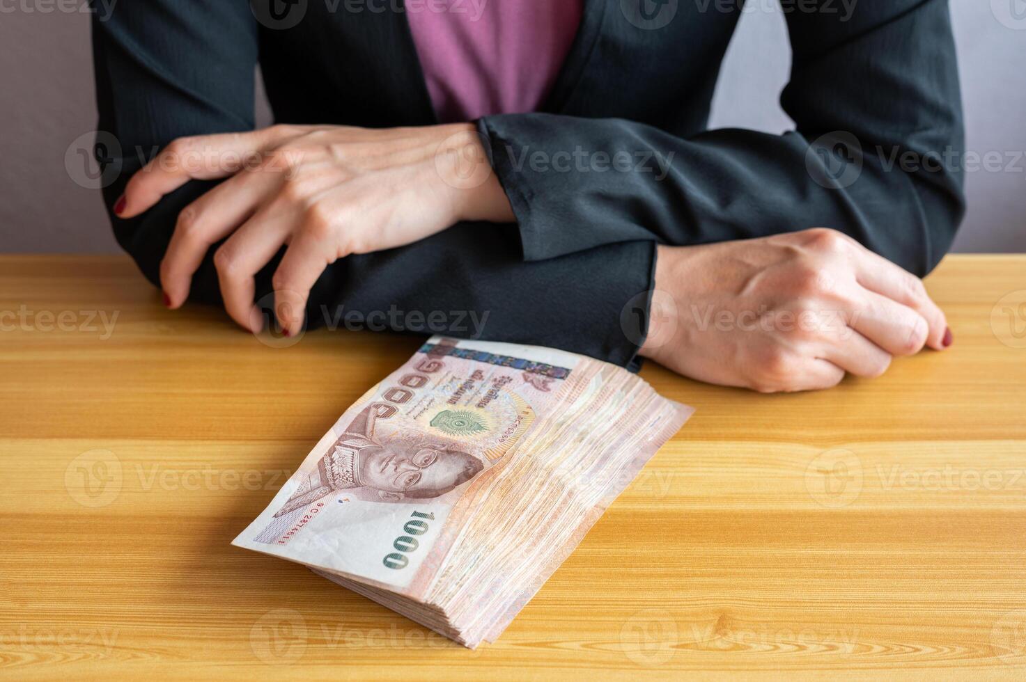 An accountant woman sitting and cross her arms before counting or giving Thai baht banknotes to someone. The baht is the official currency of Thailand. photo