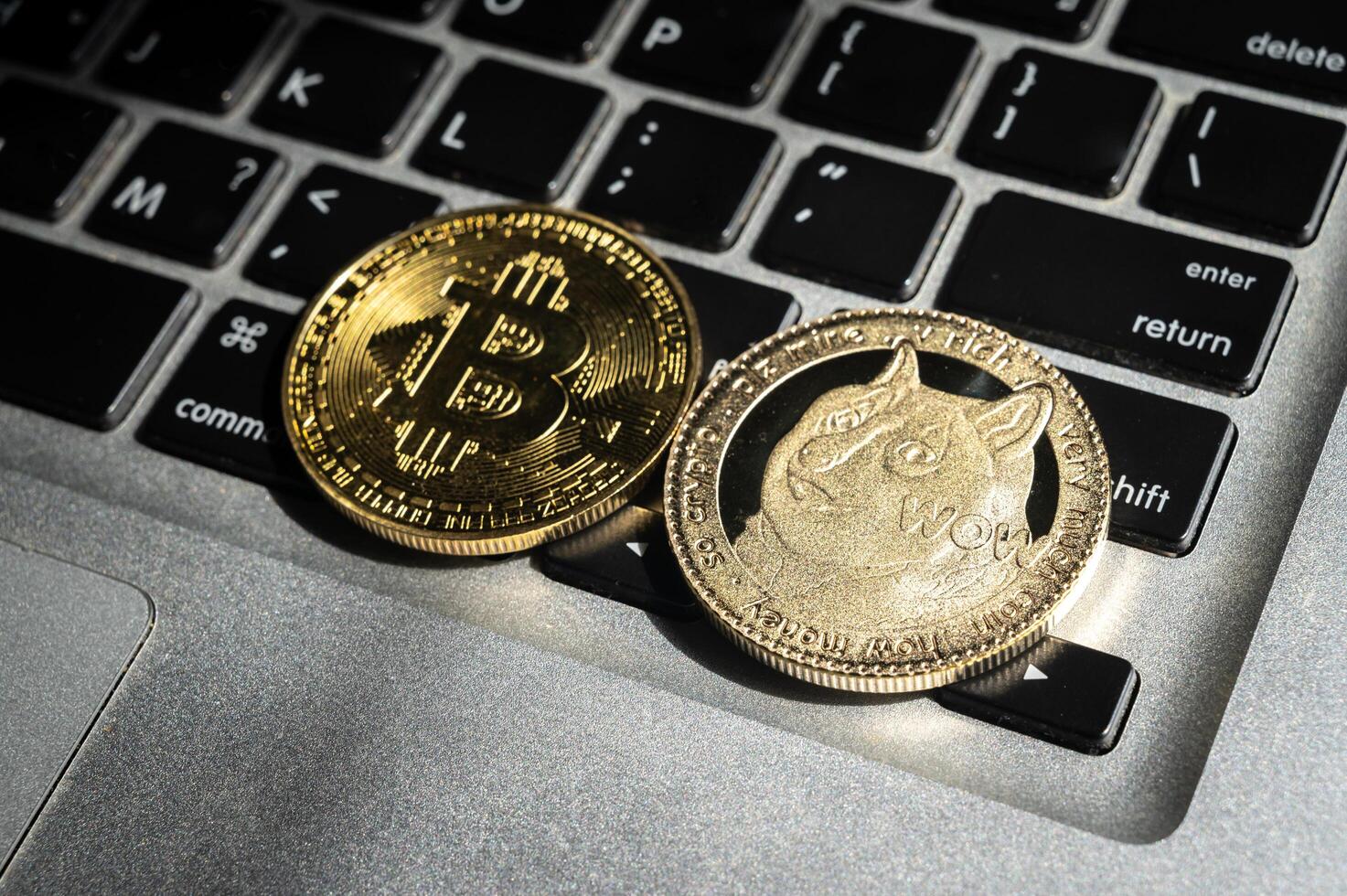 Bitcoin and Dogecoin tokens on computer keyboard. photo