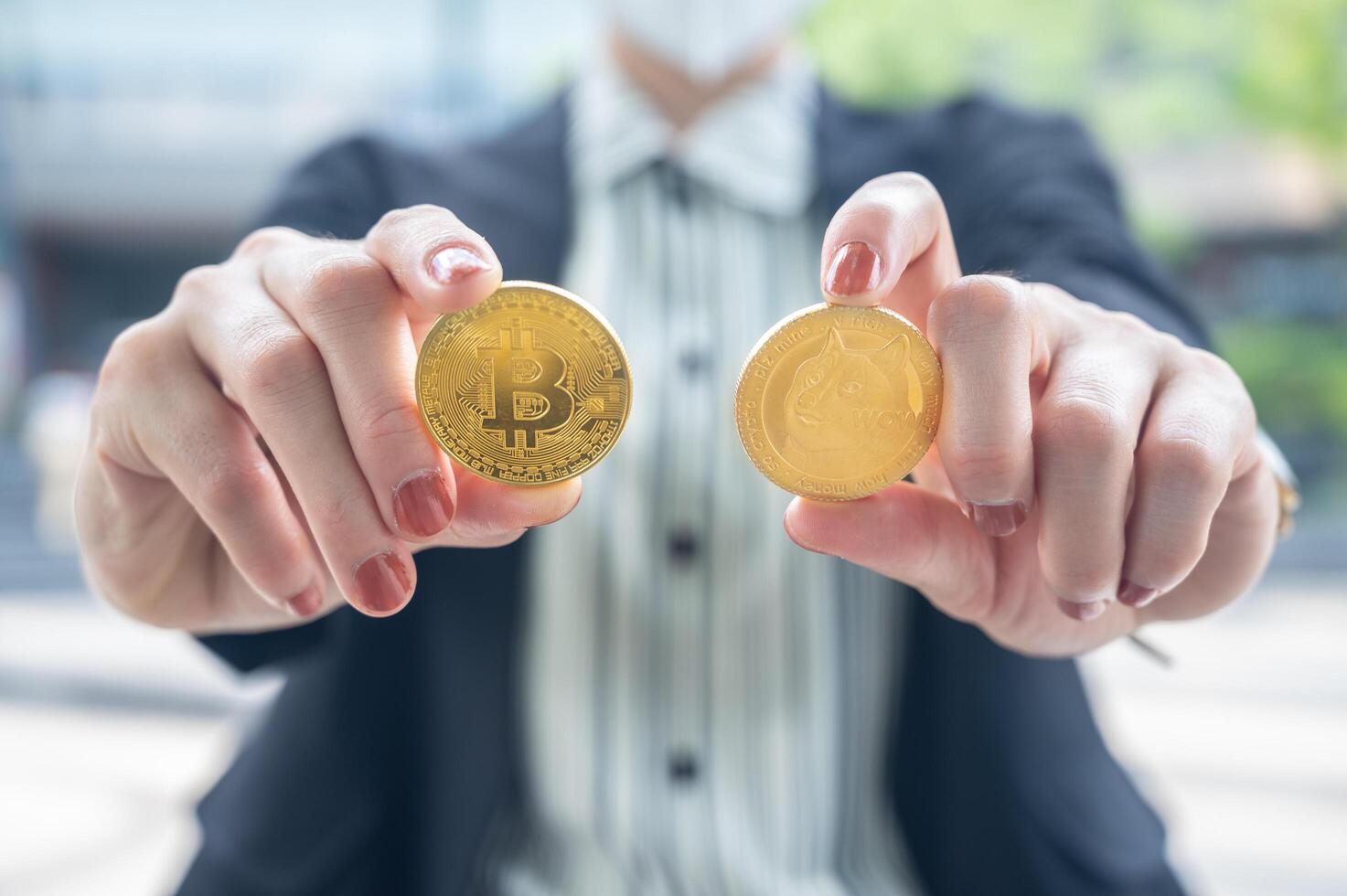 Close up of businesswoman holding Bitcoin and Dogecoin tokens. photo