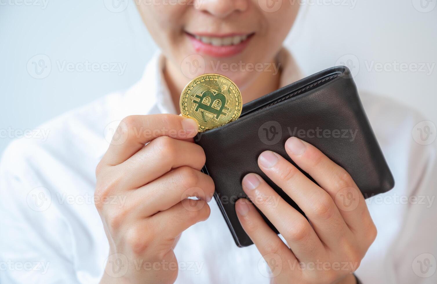 Happiness woman holding leather wallet with a golden Bitcoin token in her hands. Bitcoin is one of the popular cryptocurrency, a virtual currency or a digital currency. photo